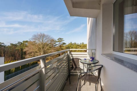 A balcony view with outdoor seating, overlooking a lush green area for relaxing moments.