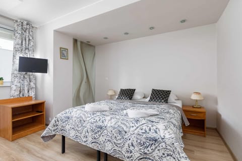A cozy bedroom featuring a double bed with patterned bedding, wooden bedside tables, and soft lighting.