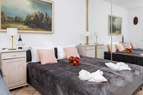 A cozy bedroom with a double bed, soft bedding, and elegant decor featuring a classic painting.
