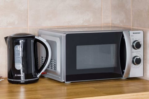 A sleek microwave and kettle placed on a spotless countertop. The clean, modern design emphasizes functionality and style.