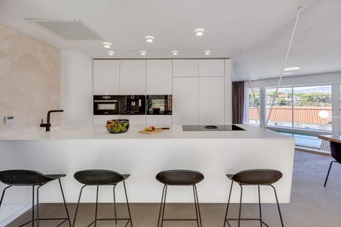 Kitchen equipped with oven, microwave, coffee machine and kitchen island with high chairs in the luxury villa Ideali on the island of Hvar