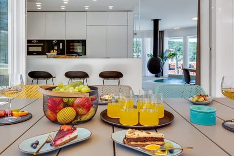 A dining table on the outdoor terrace with served cakes and a view of the interior of Croatia luxurious Ideali villas in Vrboska on Hvar