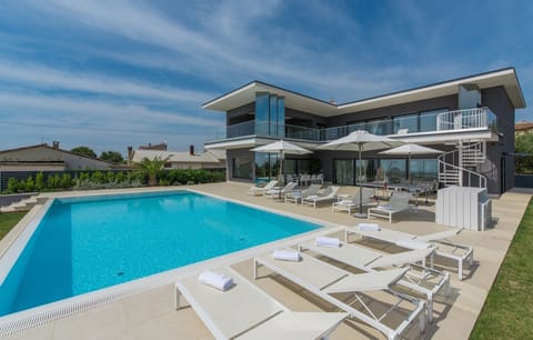 Outdoor terrace with deckchairs for sunbathing by the pool in the luxury villa Nimai Luce in Istria