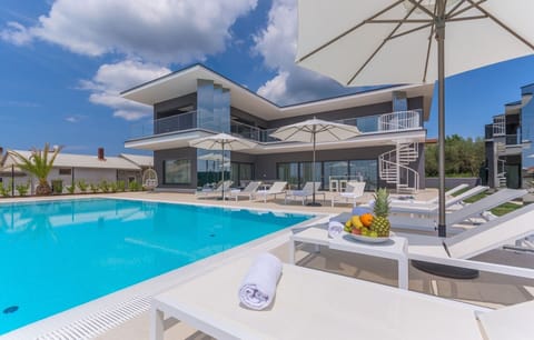 Sunbed with sunbeds and umbrellas next to the outdoor pool in the luxury villa Nimai Luce in Kaštelir in Istria