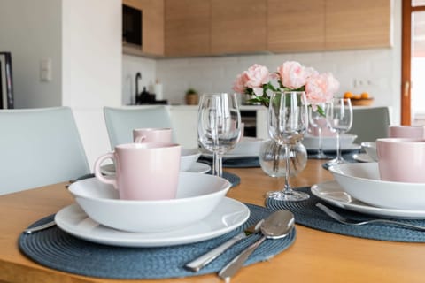 A well-decorated dining table with pastel-colored plates, glassware, and fresh flowers as a centerpiece.