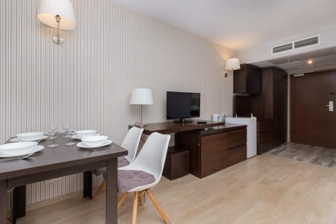 A dining area with a desk, lamp, and TV for added convenience.
