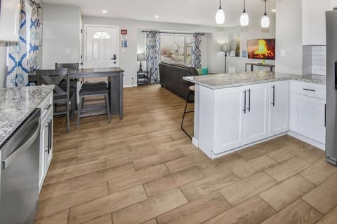 From this angle, you’ll appreciate the open-concept layout, where the kitchen seamlessly flows into the dining area. The sleek countertops and modern appliances in the kitchen are complemented by the inviting 4-seater dining table.