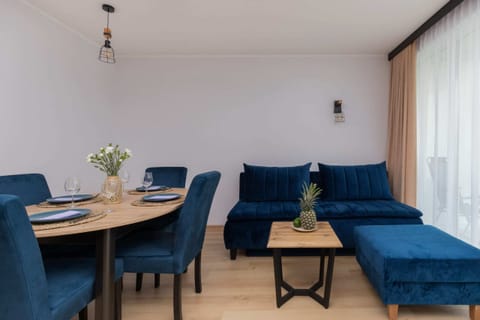 A spacious dining and living area with a modern dining table set for four and a cozy blue sofa in the background.

