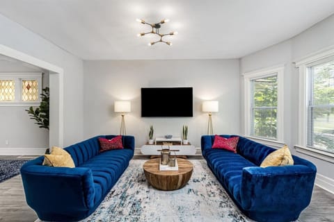 Sunlit living room with plush blue velvet sofas and mounted flat screen