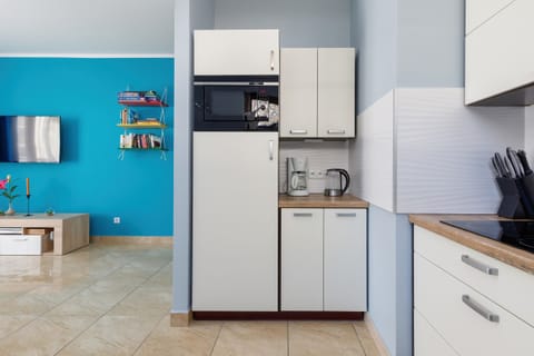 A compact, functional kitchen featuring white cabinets, turquoise accents, and all necessary appliances.