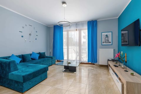A bright, modern living room with a turquoise sofa, decorative pillows, and a flat-screen TV mounted on the wall.