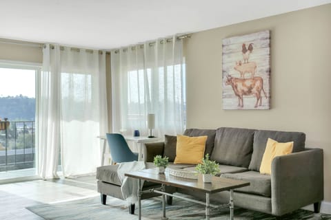Cozy living room with natural light, desk setup, and serene hillside views.