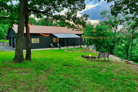 Front entrance with canopy, string lights, and fire pit