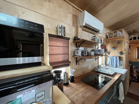 Kitchen has an induction stove top with two burners. Two pots and two pans are provided. AC /heating unit with remote.  Coffee pot and grinder provided.  Microwave. (no oven) 