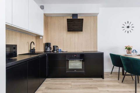 A compact kitchen with modern appliances, including a coffee maker and an electric kettle, on a light wood countertop.