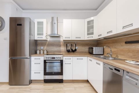 A modern kitchen with white cabinets, built-in appliances.