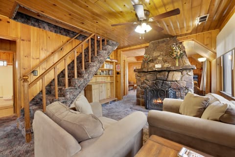 Cozy mountain living room with a stone fireplace, comfy seating, and smart TV—perfect for relaxing evenings, movie nights, and warm cabin vibes after outdoor adventures.