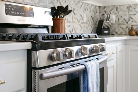 Close up of stainless steel gas range and oven in kitchen - Modern appliances ready for cooking family meals with ease - Contemporary backsplash design adds detail to the kitchen