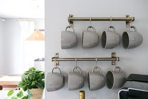 Mug rack with neatly arranged cups above coffee maker - Stylish and functional setup for the kitchen station - Ready for fresh brews anytime during your stay