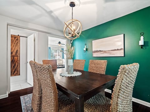 Gather for meals or game nights in this stylish dining area featuring a bold green accent wall, woven chairs, and warm lighting 🍽️🌿 The open layout flows seamlessly into the modern kitchen for easy entertaining!