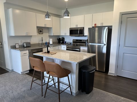 Modern kitchen with granite countertops, stainless steel appliances, and tons of kitchenware 