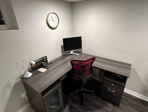 Basement workspace with monitor, desk lamp, and office supplies.