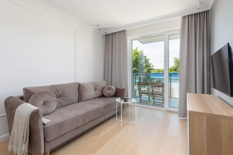 A spacious living room featuring a comfortable sofa, TV and access to balcony.