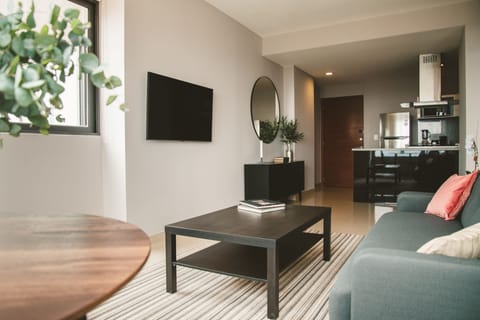 Step into the living room bathed in abundant natural light, featuring a comfortable couch and an open-concept kitchen.