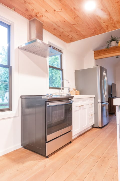 Full oven with large refrigerator and farmhouse sink.