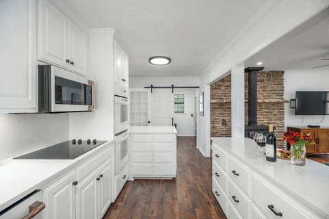 Unleash your culinary creativity in our pristine white kitchen, featuring luxurious white and gold designer appliances, including an electric flat top stove, double ovens, dishwasher, and full refrigerator.