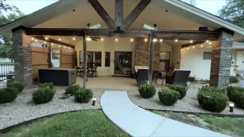 Covered patio with two ceiling fans, four wicker seats and a card table and chairs and a deck box holding outdoor toys.