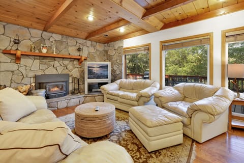 Cozy mountain living room with a stone fireplace, comfy seating, and a TV—perfect for relaxing evenings, movie nights, and warm cabin vibes after outdoor adventures.