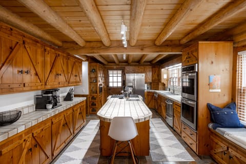 Well-lit chef's kitchen w/ island, double ovens, prep sink, window seat
