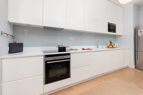 A sleek kitchen with white cabinetry, built-in appliances, and a bright, minimalist design.
