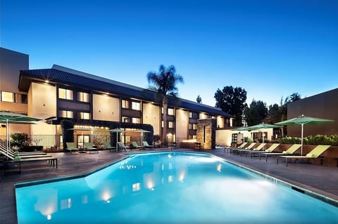 Unwind poolside at dusk with glowing lights and loungers.