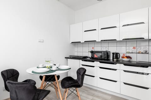 A view of the kitchen and dining area, featuring a round table with modern chairs.

