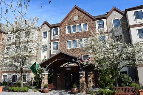 Arrive to blooming trees framing a welcoming covered entrance.