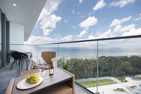 Spacious balcony overlooking lush greenery, with a cozy dining setup perfect for morning coffee.