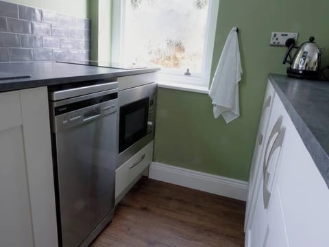 Galley kitchen area with convection oven / microwave, dishwasher and fridge.