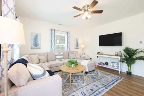 Bright living room w/ cozy seating, wall-mounted TV & natural light streaming through large windows