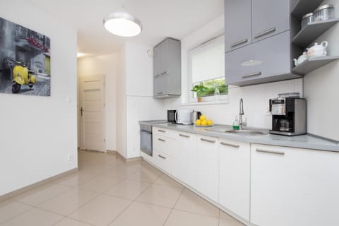 A modern kitchen with gray and white cabinets, a tiled backsplash, and essential appliances.