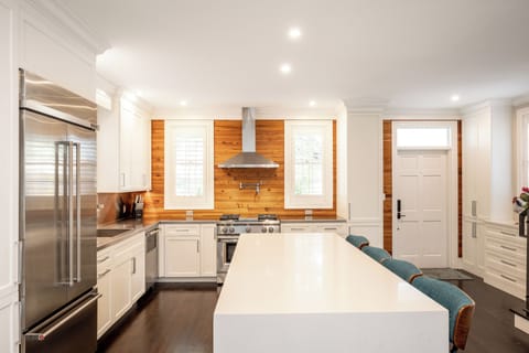 A white, quartz waterfall island has seating for four and a built-in microwave