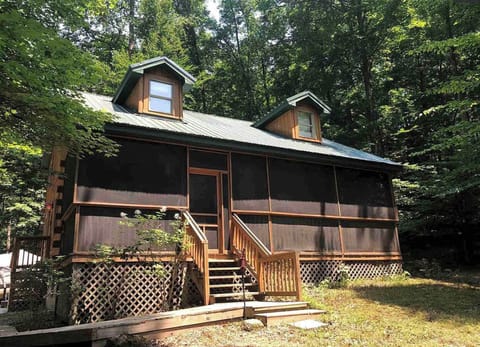 TokaTime log cabin has a long screen-in porch and a woodsy view.