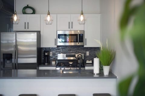 first level fully functioning kitchen includes stainless steel appliances, industrial pendant lighting, coffee supplies, cooking utensils & more