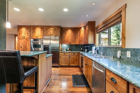 The fully equipped kitchen features stainless steel appliances including two ovens, spacious counters for meal prep, and a kitchen bar with seating for four.