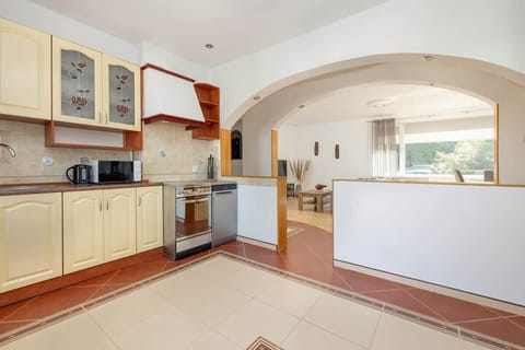 Fully equipped kitchen with ample cabinet space, tiled flooring, and all the essential appliances you need for home cooking.