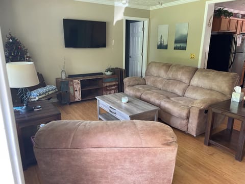 Living room w/ smart TV, recliner chair and dual recliner couch.
