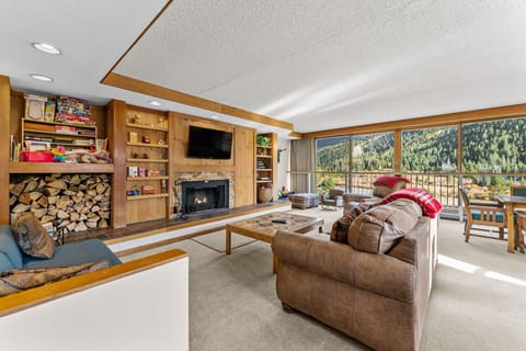 Spacious living area with open floor plan, wood-burning fireplace, and flatscreen TV.
