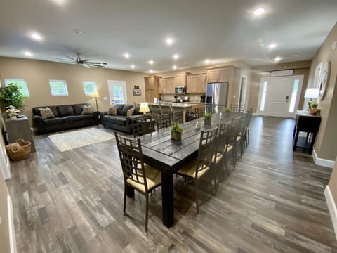 Large custom build dining table seats 14 with 6 island seats on an open kitchen/dining/living space.