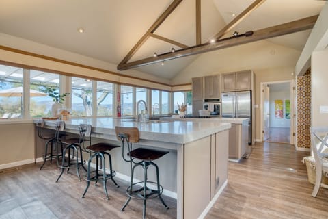 Fully-equipped kitchen with a large island, gas range, barstool seating, and a full suite of appliances.